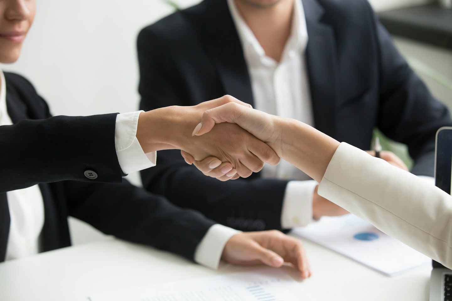 Deux professionnels se serrent la main au-dessus d'un bureau dans un bureau.