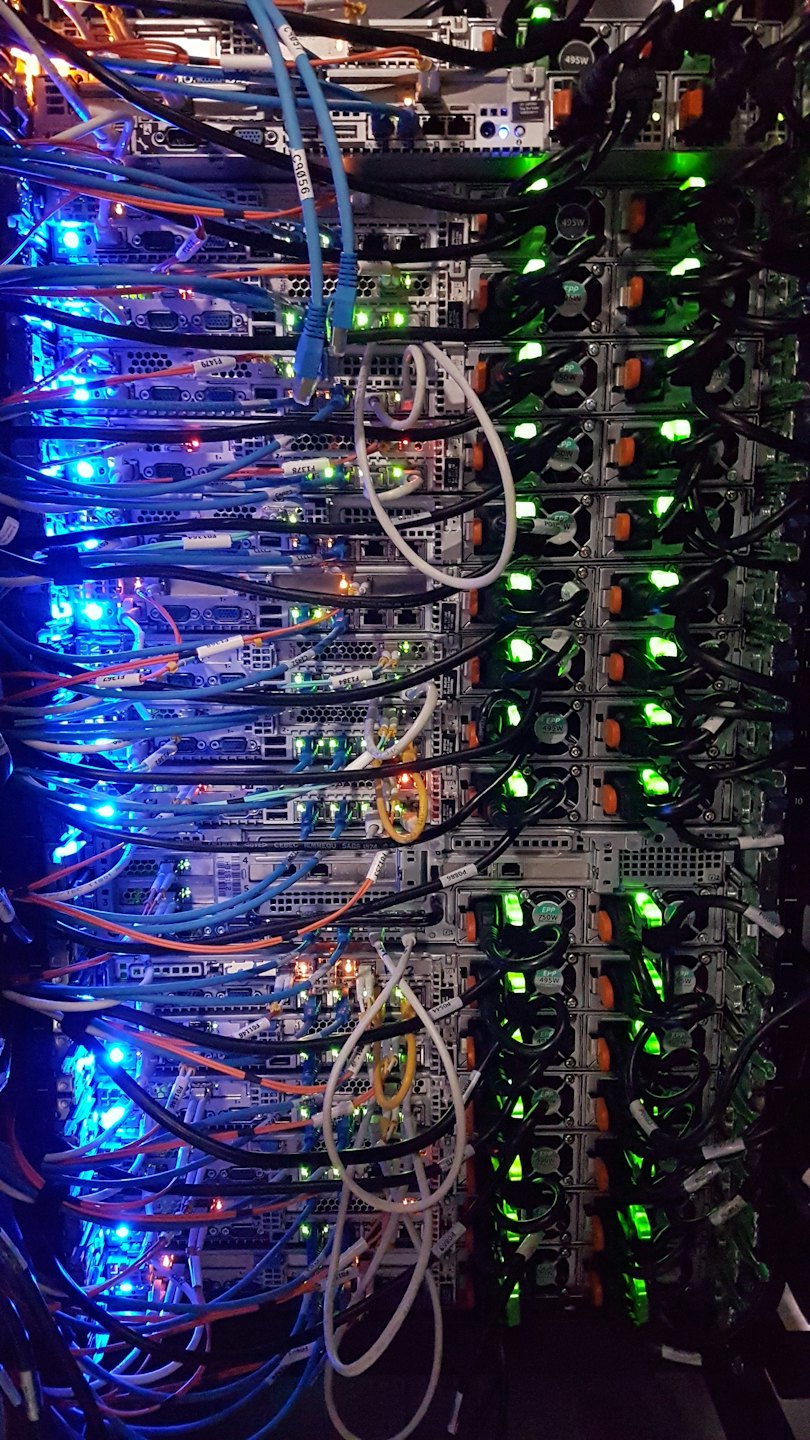 Rack de serveurs avec de nombreux câbles colorés et des lumières vives.